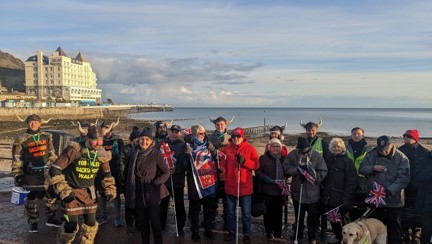 Backward walking fundraisers dressed as Vikings at the start line of their challenge with supporters in the background including blind veterans