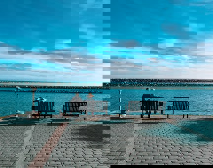 A photo of two older people sitting on a bench at the seafront