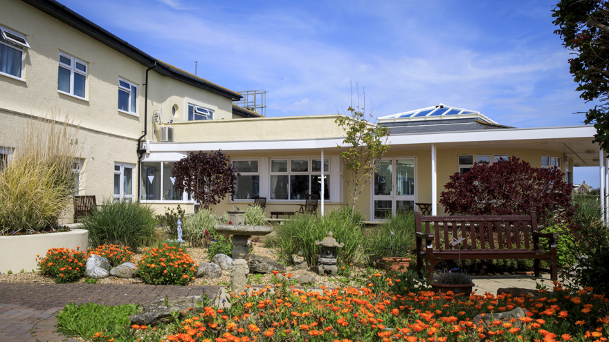 The garden at the entrance to our new centre, with a bench and an array of bright orange flowers