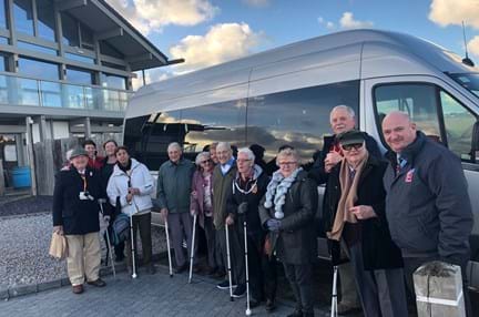 A group of blind veterans and staff gathered together in front of a van