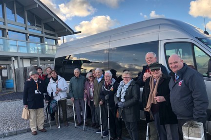 A group of blind veterans and staff gathered together in front of a van