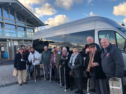 A group of blind veterans and staff gathered together in front of a van