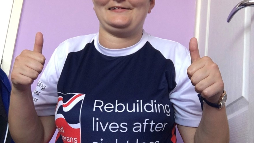 Laura pictured smiling and putting her thumbs up, wearing a Blind Veterans UK top