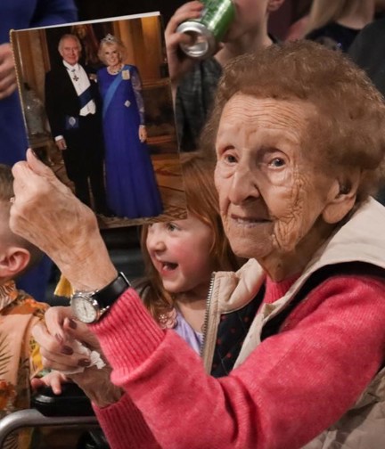 Blind veteran Margaret is sitting down and showing her birthday card from the King to the camera