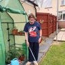 Noeline wearing Blind Veterans UK t-shirt stood in her garden holding her cane