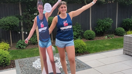 Evie wearing a Blind Veterans UK vest standing next to a cardboard cut-out of herself