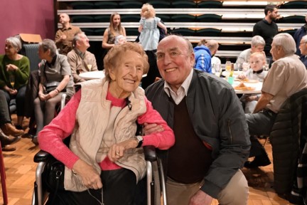 Blind veterans Margaret and Simon smiling and linking arms at her birthday party