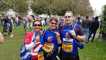 Photo of Joey, left, Angela, centre, and Andy, right holding their medals, wearing Blind Veterans UK vests after finishing the Great South Run in Portsmouth