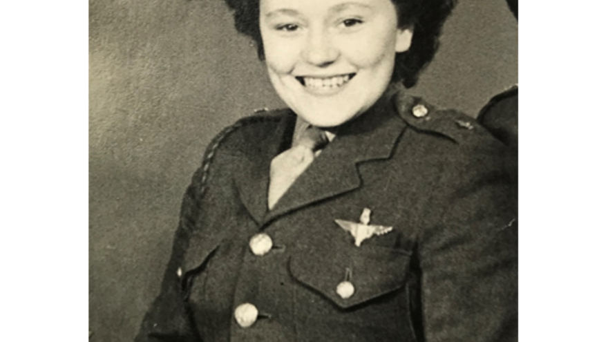 A black and white portrait of Neena during her military service, smiling in military uniform.