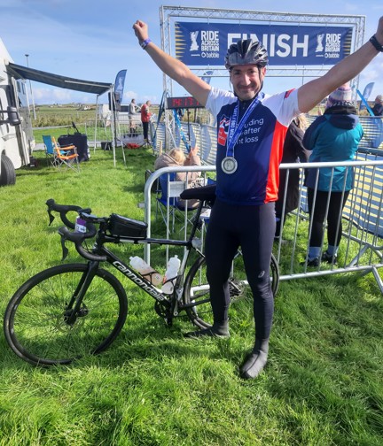 Jon celebrating with his arms in the air and medal around his neck