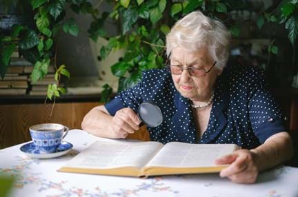 Elderly woman reading with a magnifier