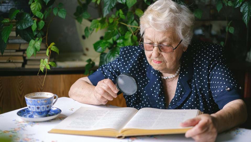 Elderly woman reading with a magnifier
