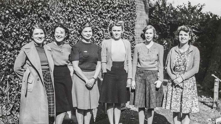 An archive photograph of a blind veteran Barbara standing outside smiling with a group of female blind veterans