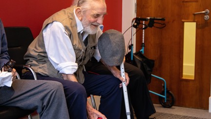 Blind veteran Ken sitting down, smiling, as he prepares to throw a small red ball