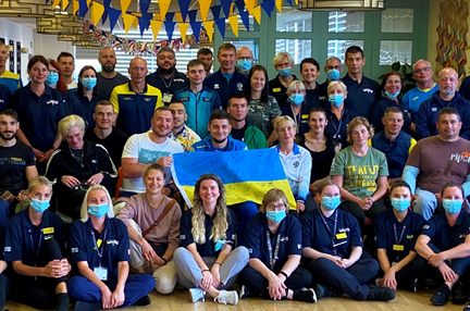 A group photo of the Ukrainian team in their training kit, holding a Ukrainian flag and joined by Blind Veterans UK staff members