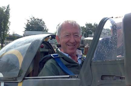Chris smiling and looking at the camera while sat in an original Second World War Spitfire plane