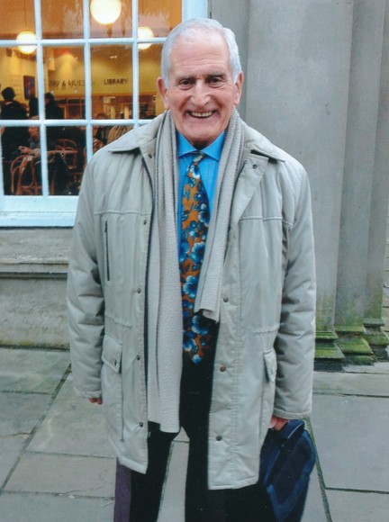 Blind veteran Geoffrey pictured standing outside, wearing a warm coat and smiling to the camera