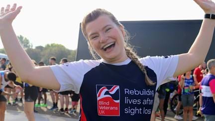 A beaming Sarah in her Blind Veterans UK sports top, waving her arms in the air.