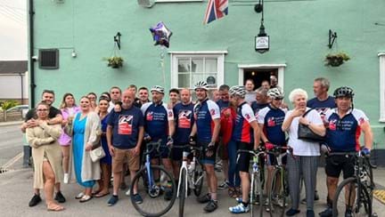 Cyclists with their support team and friends and family outside the pub