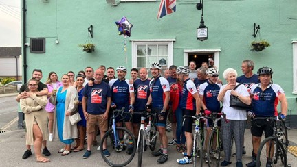 Cyclists with their support team and friends and family outside the pub