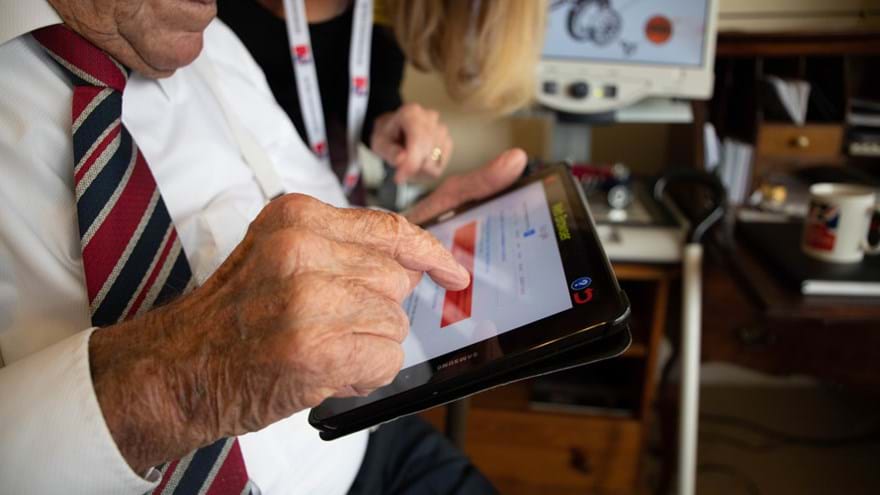 A veteran being supported by a member of staff to use a tablet