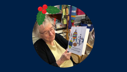 Blind veteran Joan wearing a Christmas hat, detailed with an illustration of holly.