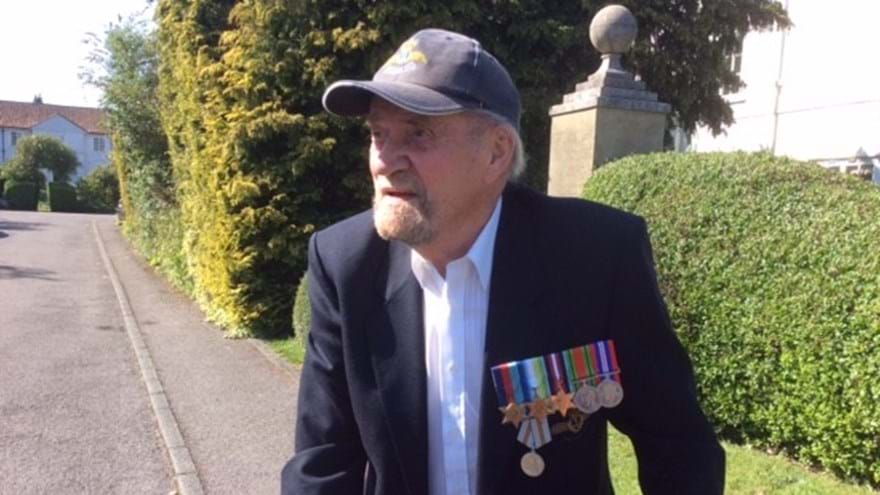Blind veteran Arnold, walking outside, wearing military medals