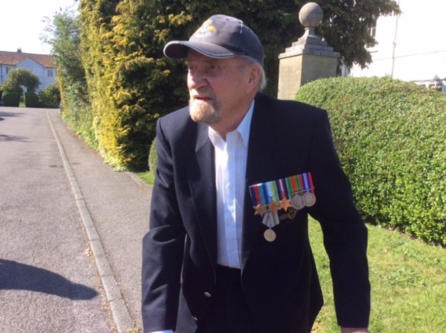 Blind veteran Arnold, walking outside, wearing military medals