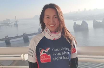 Supporter Roxana stood in front of a misty River Thames wearing her Blind Veterans UK T-shirt 