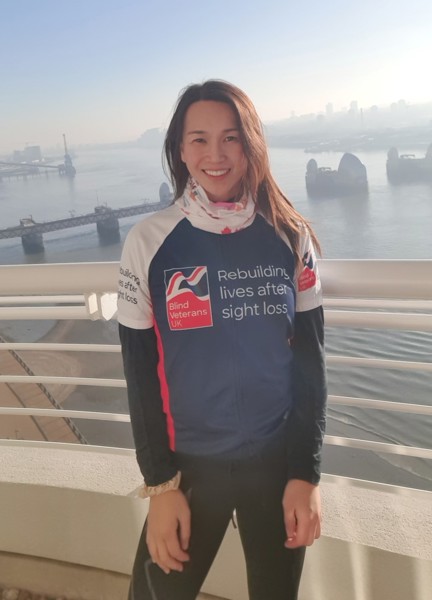 Supporter Roxana stood in front of a misty River Thames wearing her Blind Veterans UK T-shirt