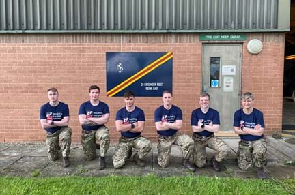 A group of supporters, kneeling, wearing matching army trousers and Blind Veterans UK t-shirts