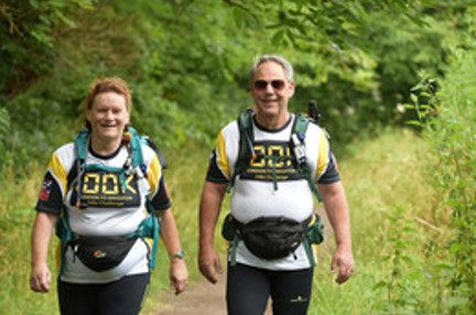 Maria and Richard walking side by side along a country footpath 