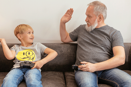 A photo of a child and elderly man playing a video game together