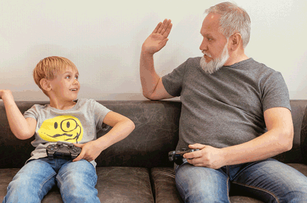 A photo of a child and elderly man playing a video game together