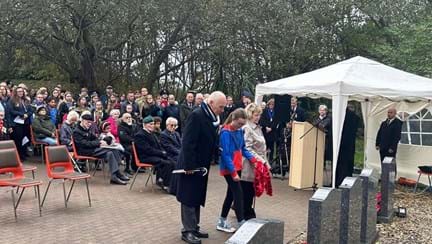 Terry and Isla have their heads bowed as Isla prepares to place the wreath at the memorial