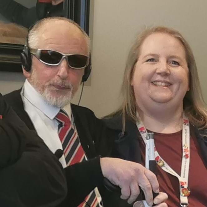 Dean wearing dark glasses with Community support worker Katherine, smiling