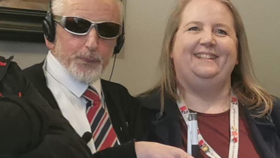 Dean wearing dark glasses with Community support worker Katherine, smiling