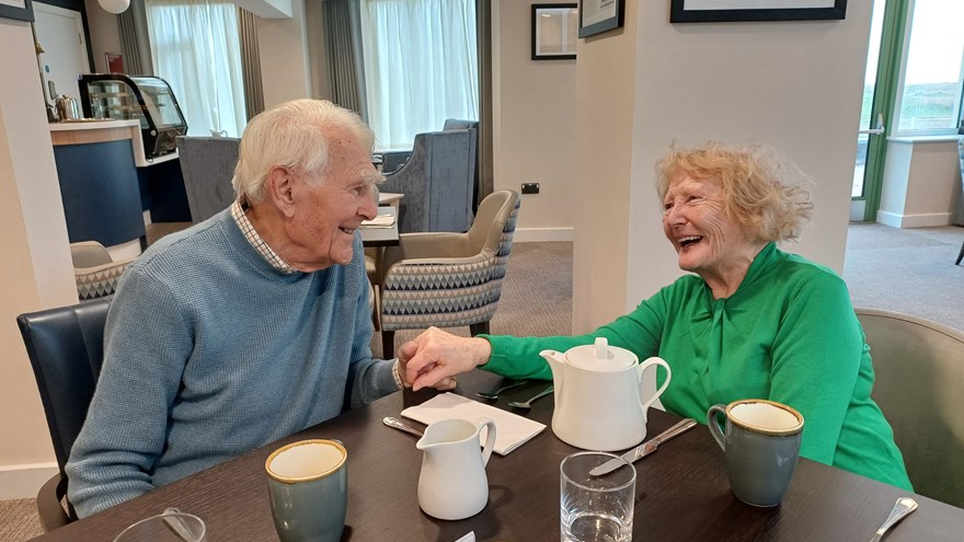 Blind veteran Patrick and his wife Jacky sit at a table at our Rustington Centre, holding hands and looking into each others eyes lovingly