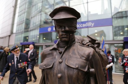 A close up photo of the Victory Over Blindess statue with blind veteran Jim in the background