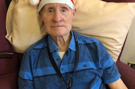 Blind veteran Arthur sitting down on an armchair, wearing a Christmas hat