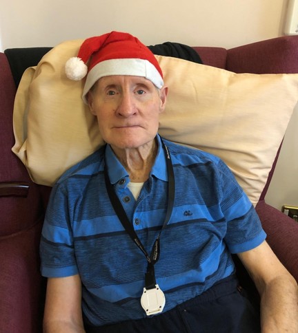 Blind veteran Arthur sitting down on an armchair, wearing a Christmas hat