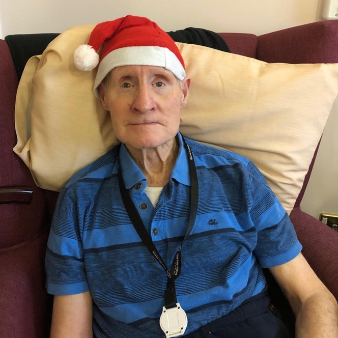 Blind veteran Arthur sitting down on an armchair, wearing a Christmas hat