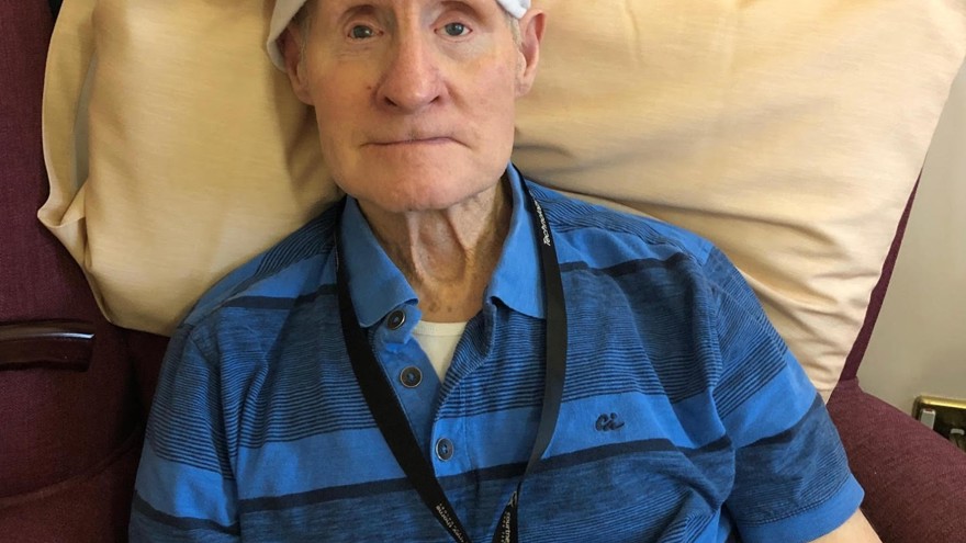 Blind veteran Arthur sitting down on an armchair, wearing a Christmas hat