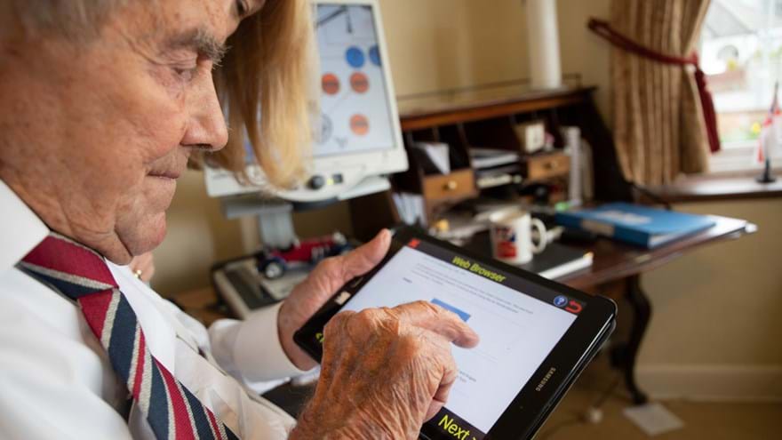 Veteran holding a tablet in one hand and using his other hand to touch the screen