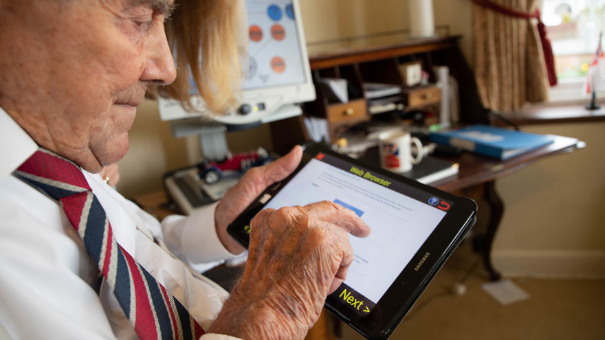 Veteran holding a tablet in one hand and using his other hand to touch the screen