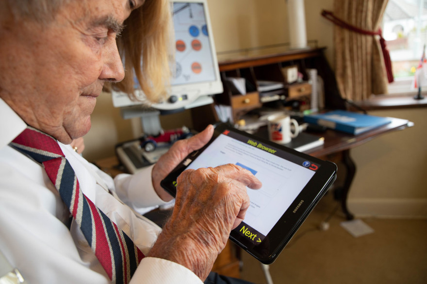Veteran holding a tablet in one hand and using his other hand to touch the screen