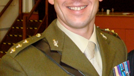 A head-shot of Justin, smiling in military uniform