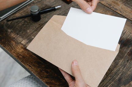 A woman's hands placing a small piece of paper into an envelope