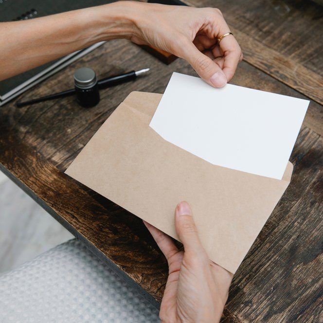 A woman's hands placing a small piece of paper into an envelope