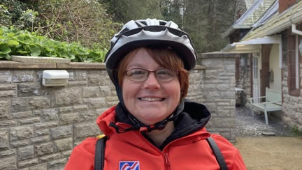 Blind veteran Sheila wearing a cycling helmet and red Blind Veterans UK jacket